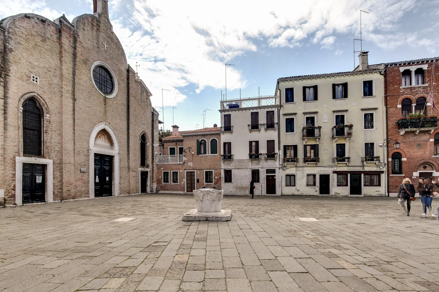 Una plaza pavimentada se extiende frente a una iglesia de ladrillo y edificios contiguos.