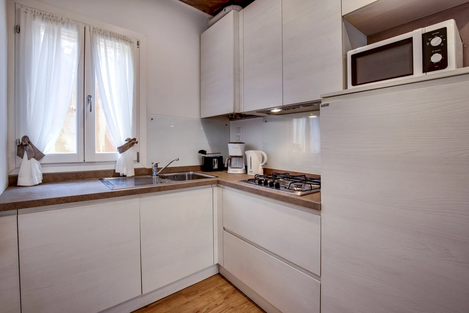 Una cocina compacta con fregadero, placa de cocina y microondas.