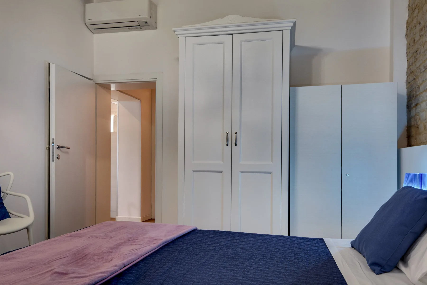 Un dormitorio con cama, armario y una puerta abierta.