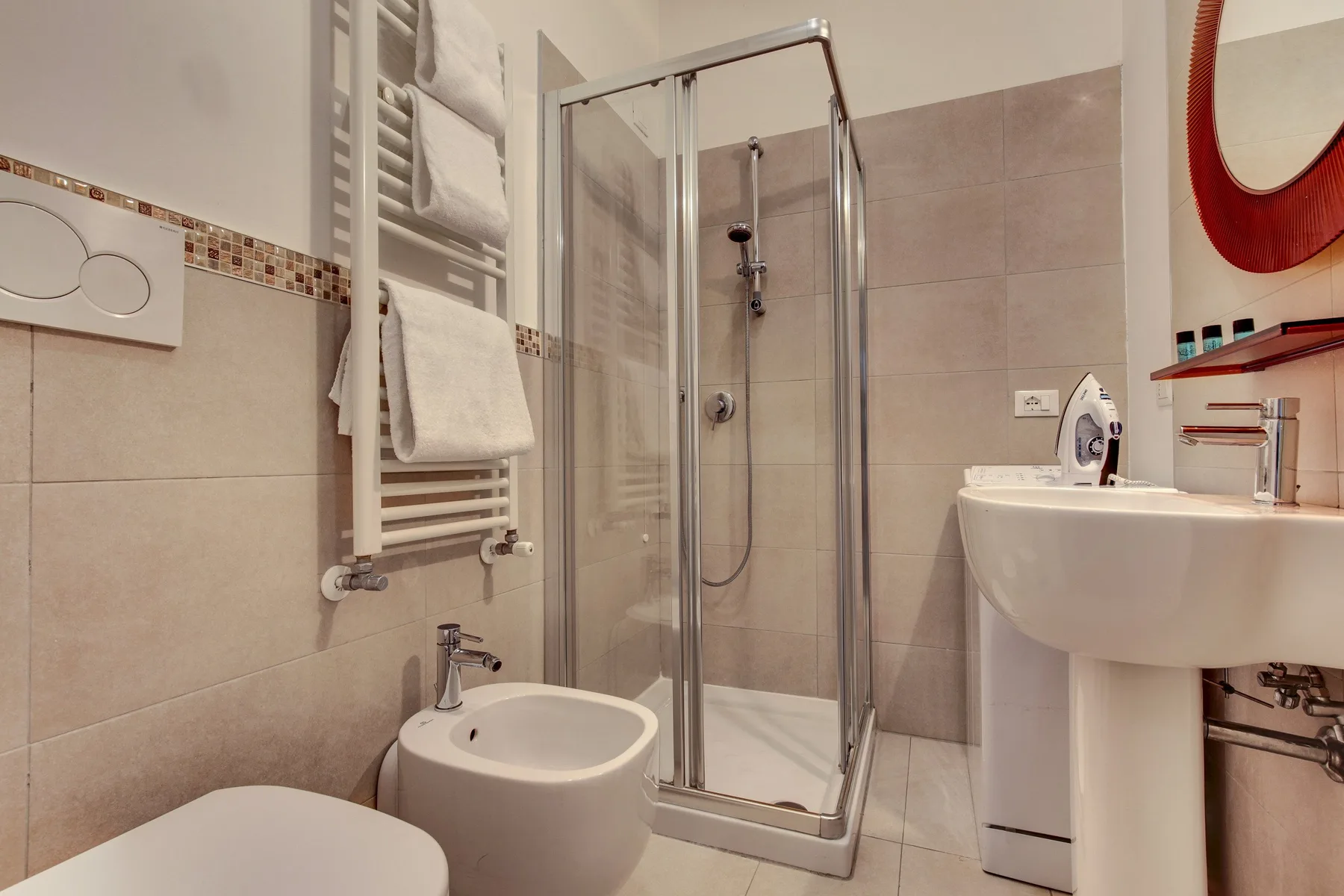 Un baño alicatado con ducha de vidrio, lavabo y bidé.