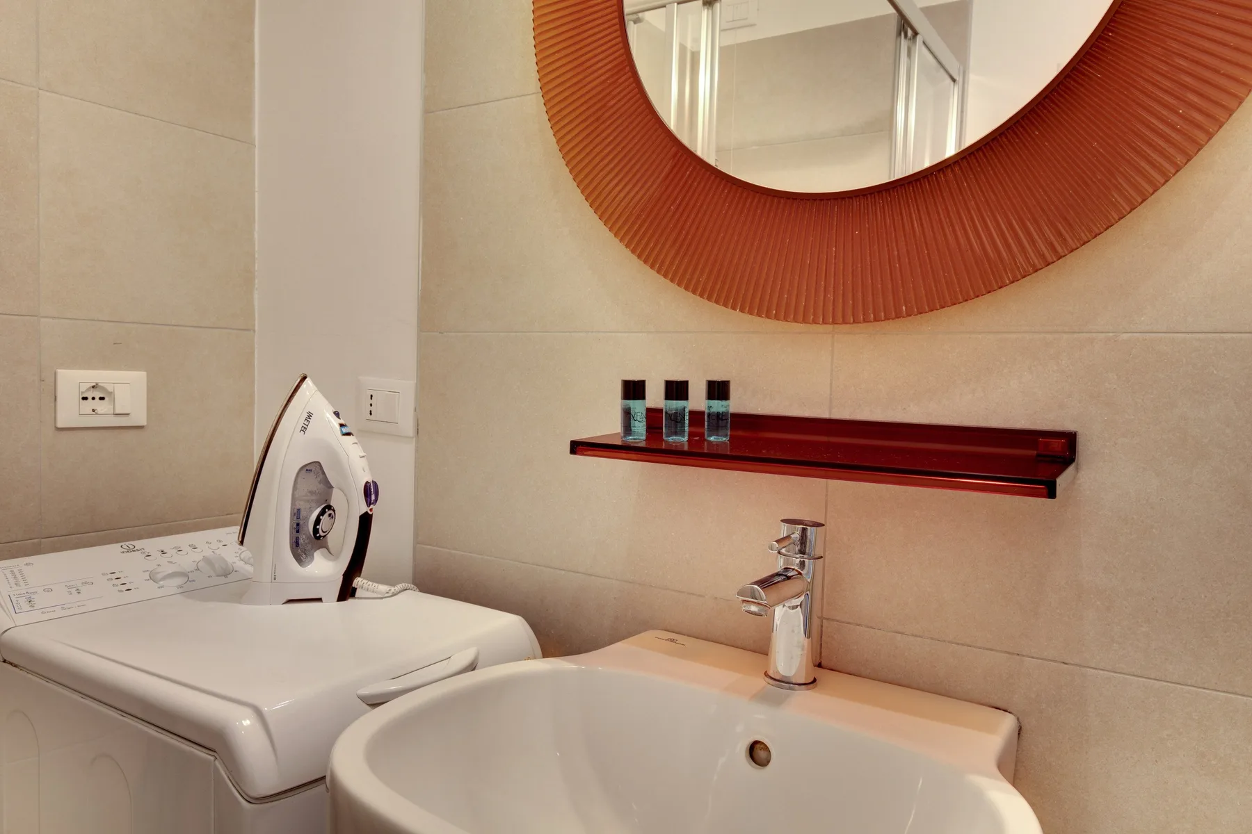 Un tocador de baño con lavabo, grifo y lavadora.