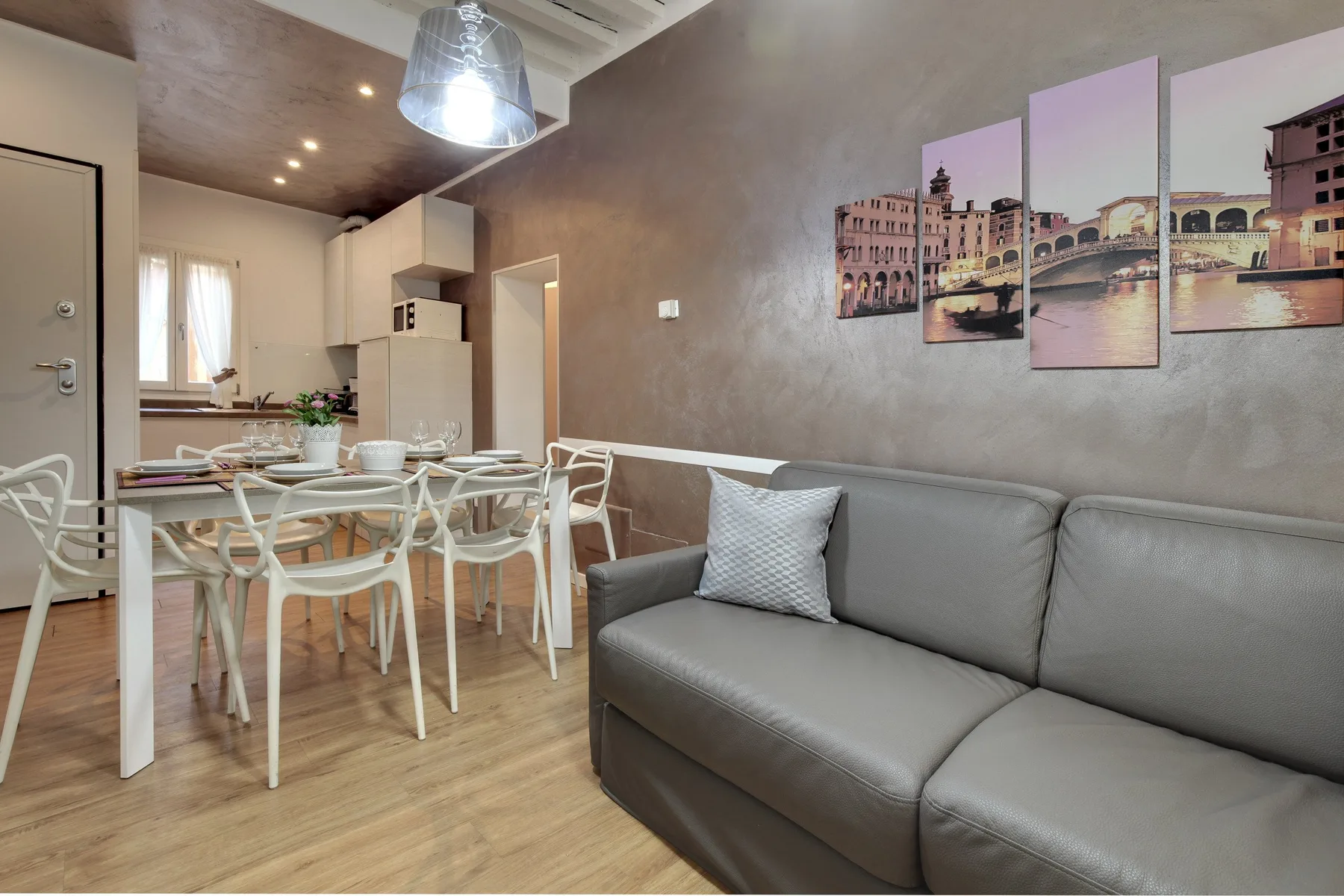 Una sala de estar y comedor con asientos grises, una mesa y arte en la pared.