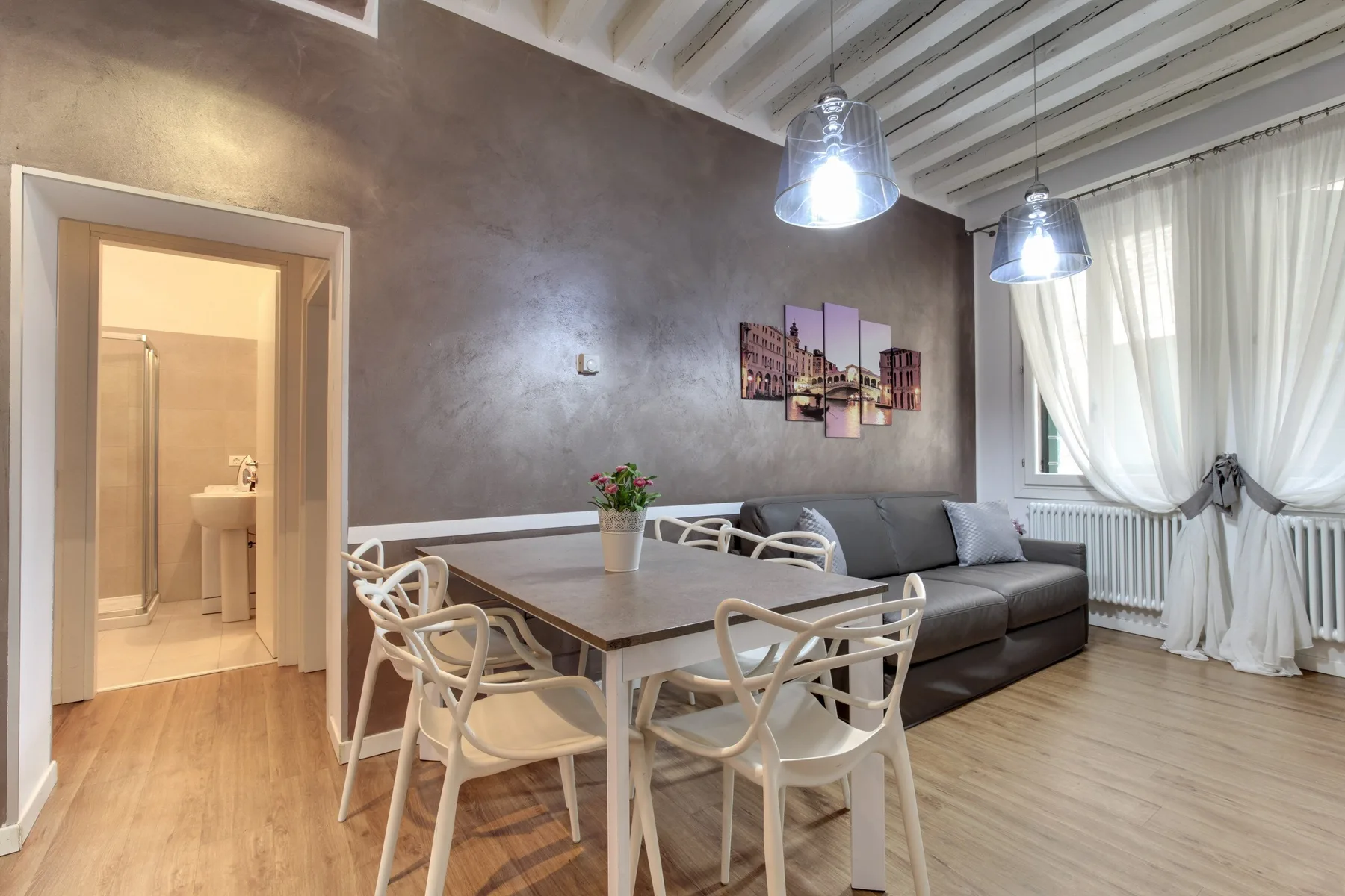 Un comedor con una mesa y sillas junto a un sofá gris.