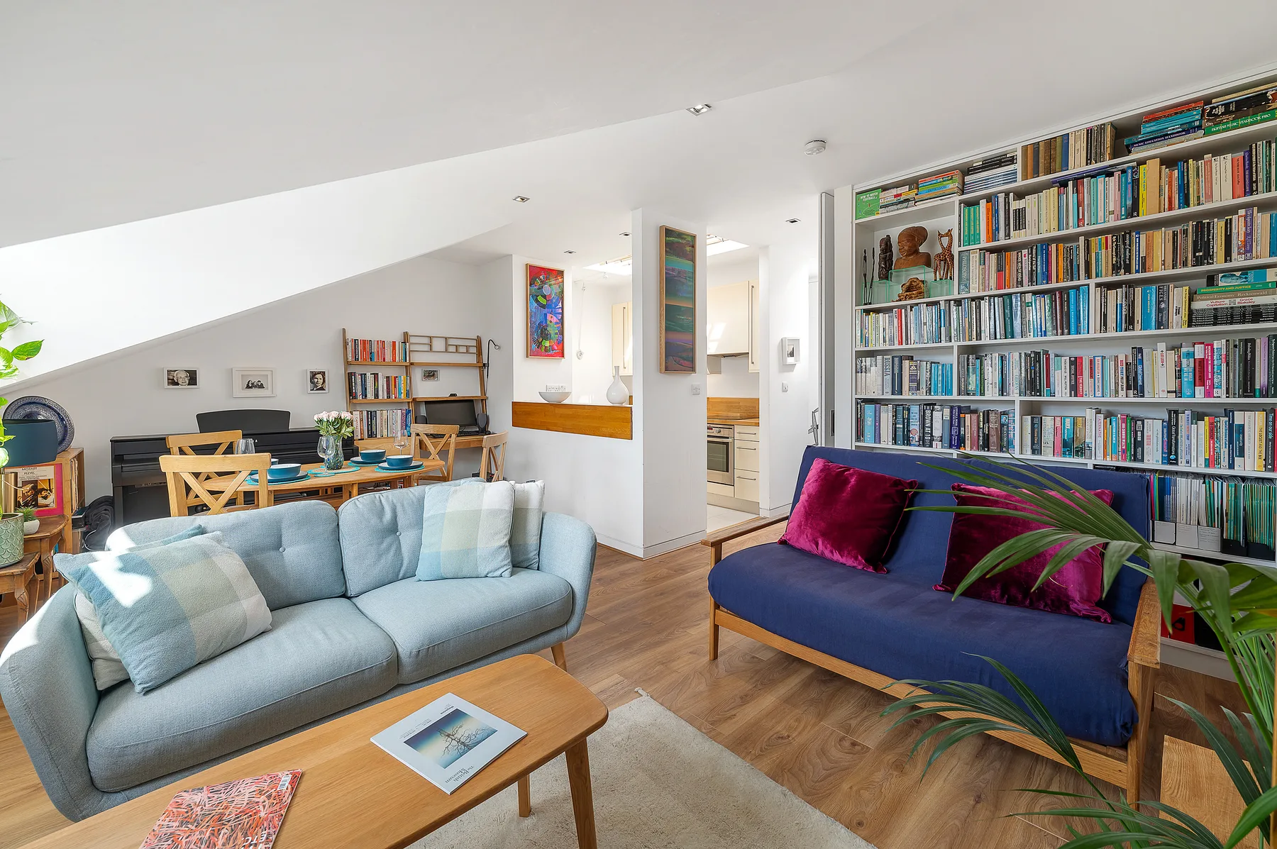 A living room with seating, a coffee table, and a large wall of bookshelves.