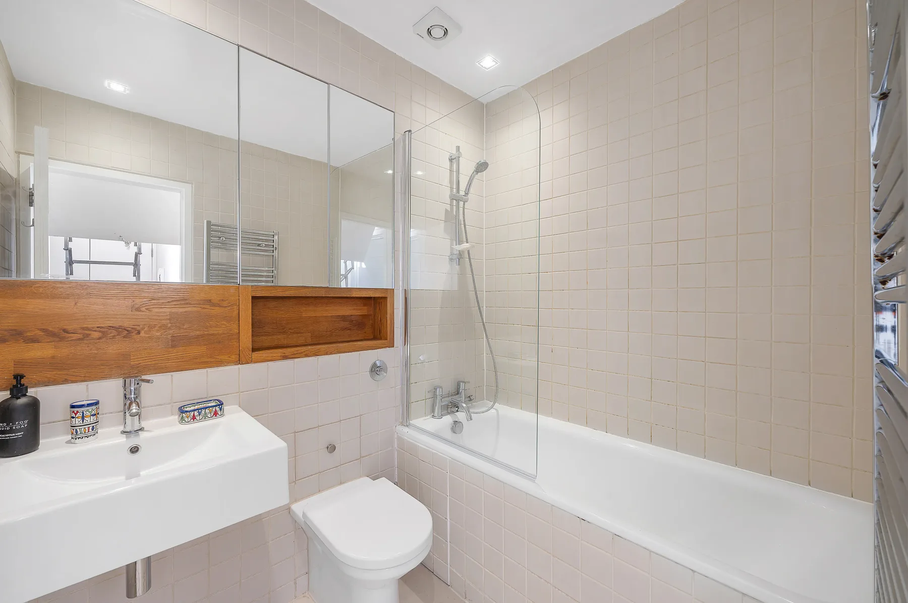 A bright tiled bathroom with a sink, toilet, and bathtub.
