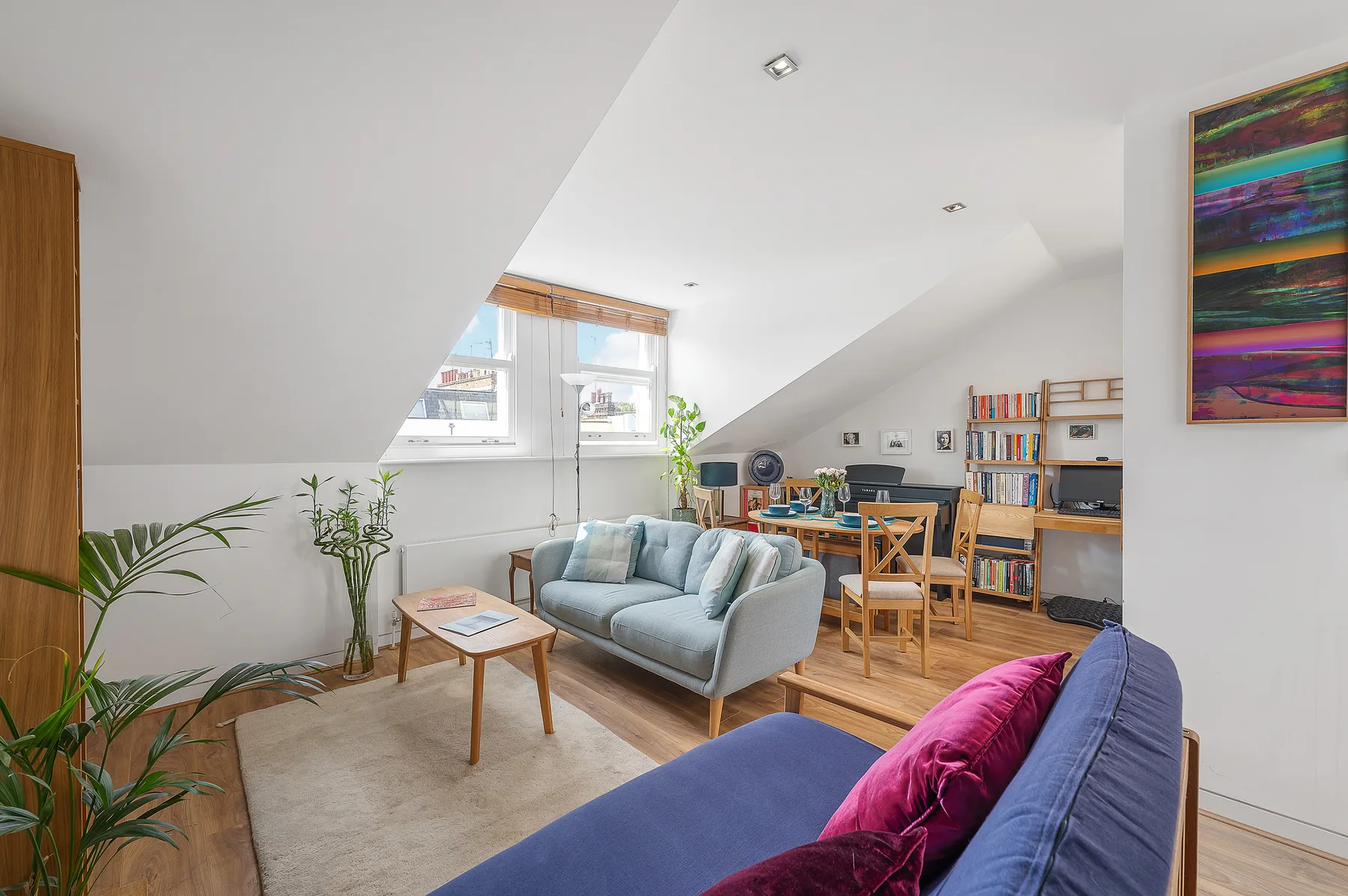 A bright attic living room with seating, a coffee table, and a dining area.