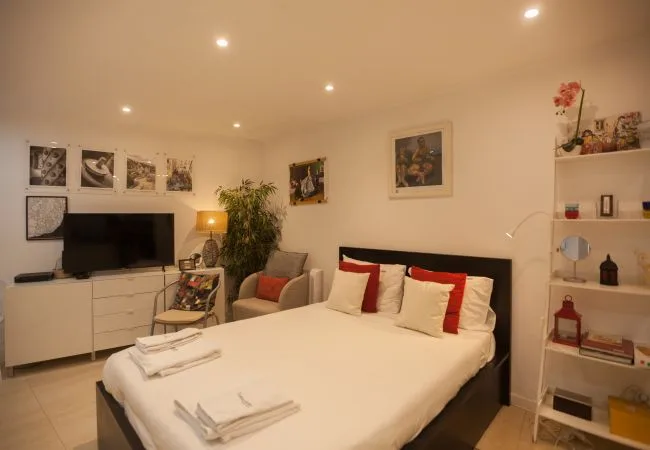 A bedroom with a neatly made bed, a television, and wall art.