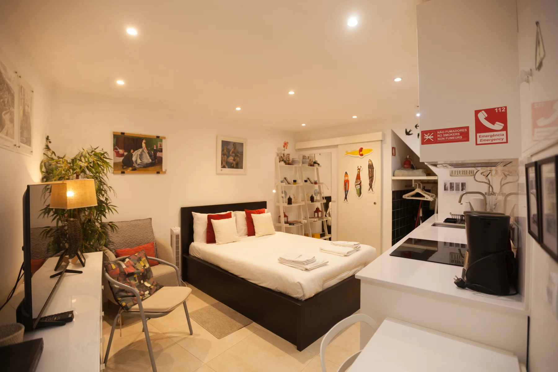 A compact studio room combines a bed, seating area, and kitchenette.