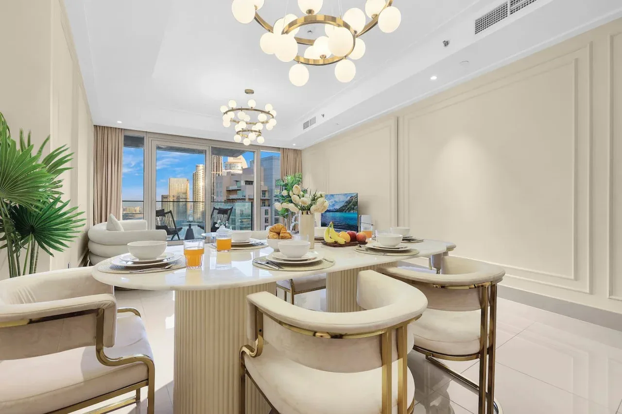 A bright dining area features a long table set beside large windows.