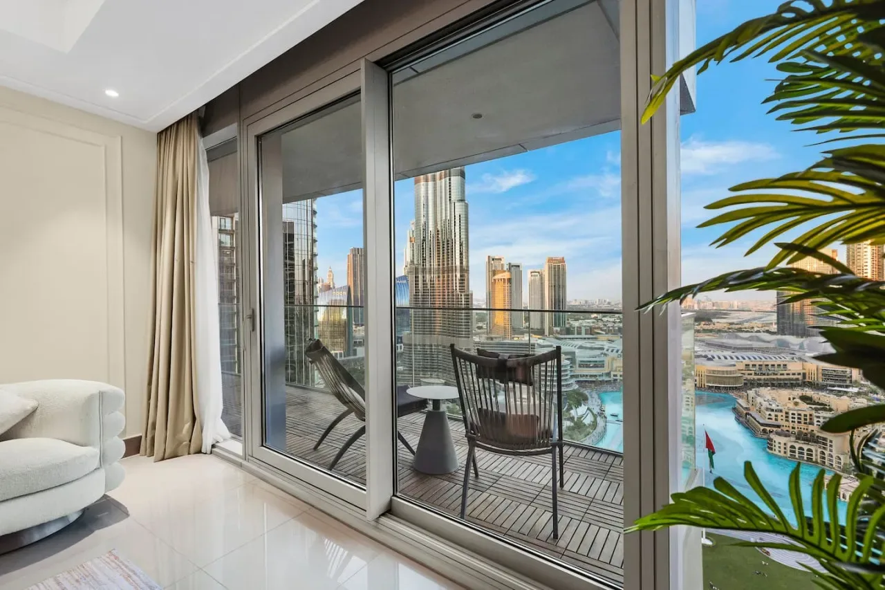 A bright living area opens onto a balcony with seating and city views.