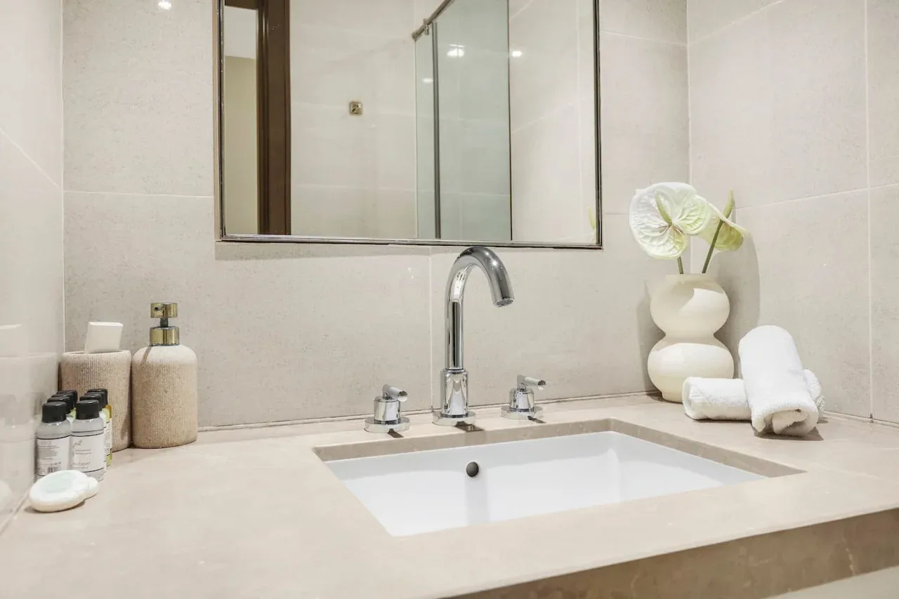 A bathroom vanity with a rectangular sink, chrome faucet, and flowers.
