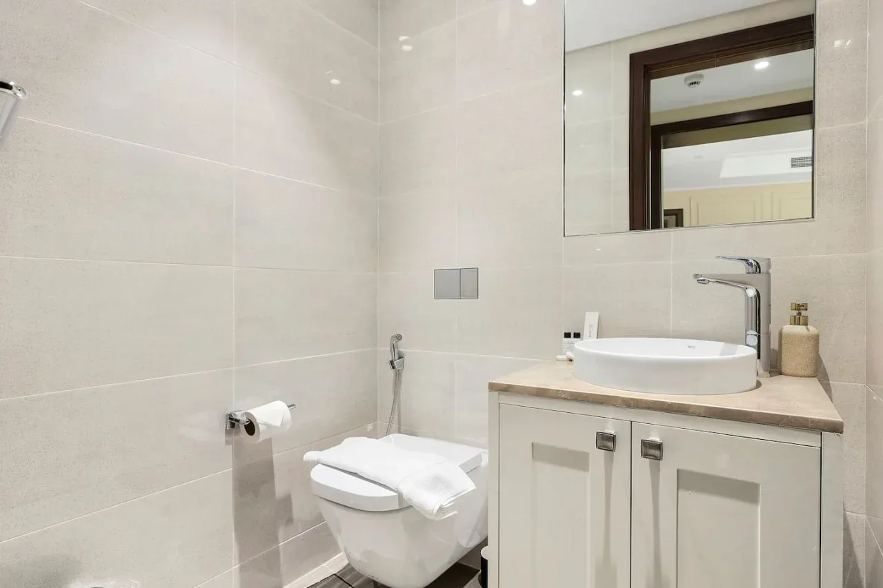 A bright bathroom with a sink vanity, mirror, and toilet.