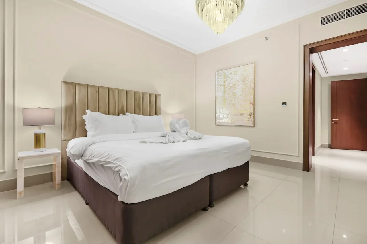 A bright bedroom with a neatly made bed and a bedside table.