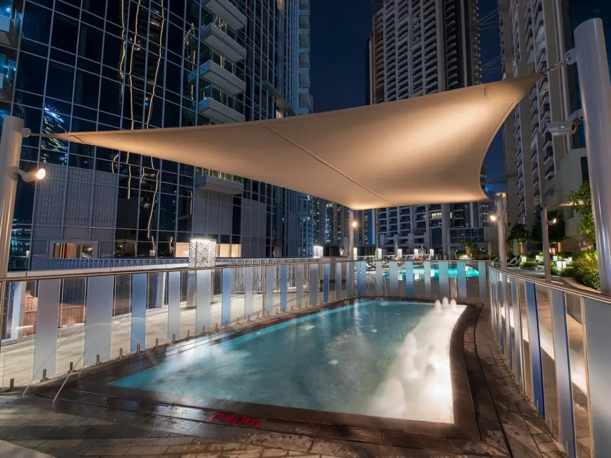 A rooftop swimming pool is surrounded by tall buildings at night.