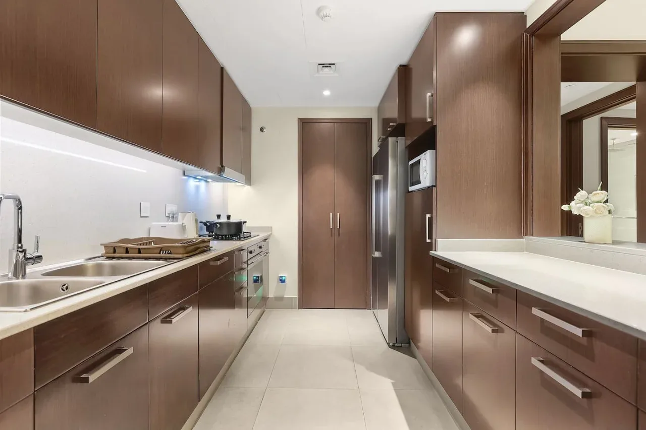 A modern galley kitchen with dark cabinets, stainless steel appliances, and a central walkway.