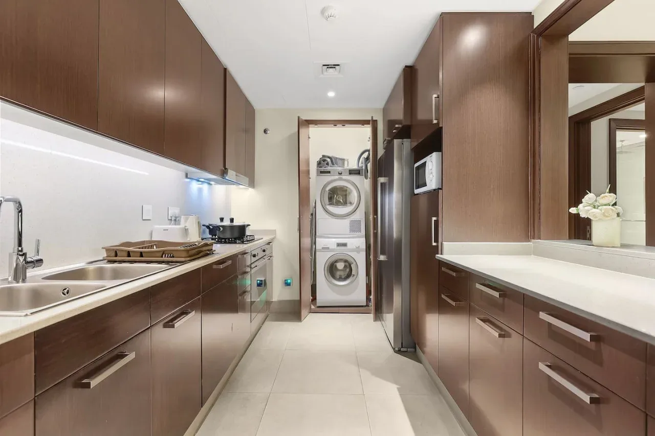 A long kitchen with dark cabinetry, a sink, and appliances.