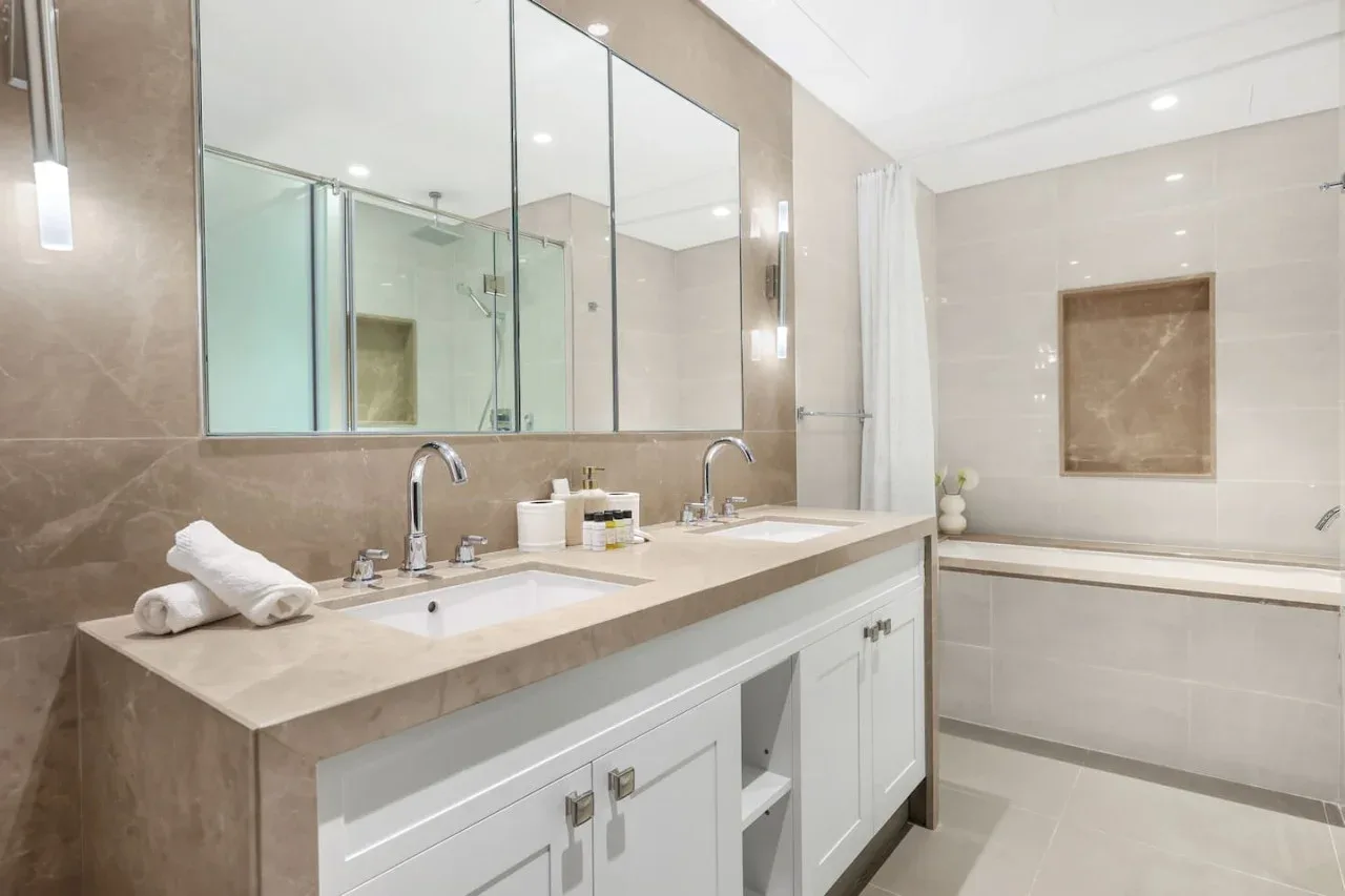 A bathroom with a long double vanity and a bathtub.