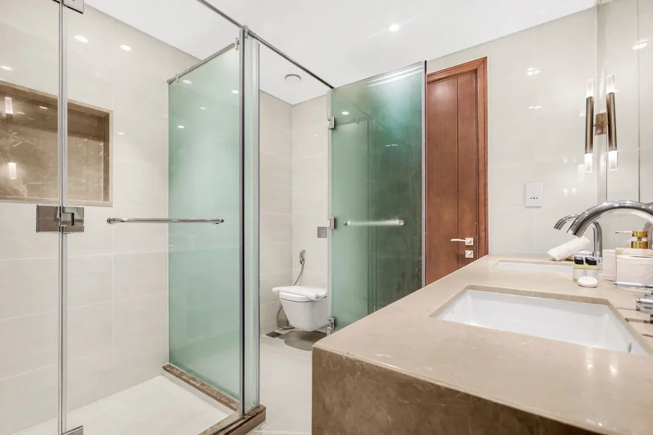 A bright bathroom with a glass shower and a wide sink counter.