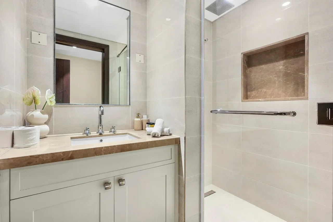 A tiled bathroom with a sink vanity and a walk-in shower.