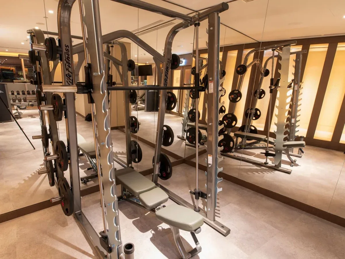 A gym with weight machines, benches, and mirrors.