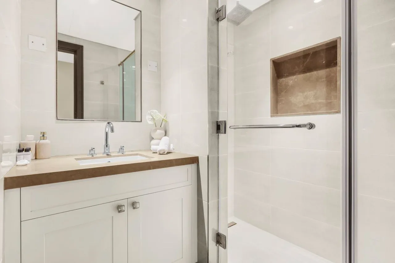 A bright bathroom with a sink vanity and a glass shower.