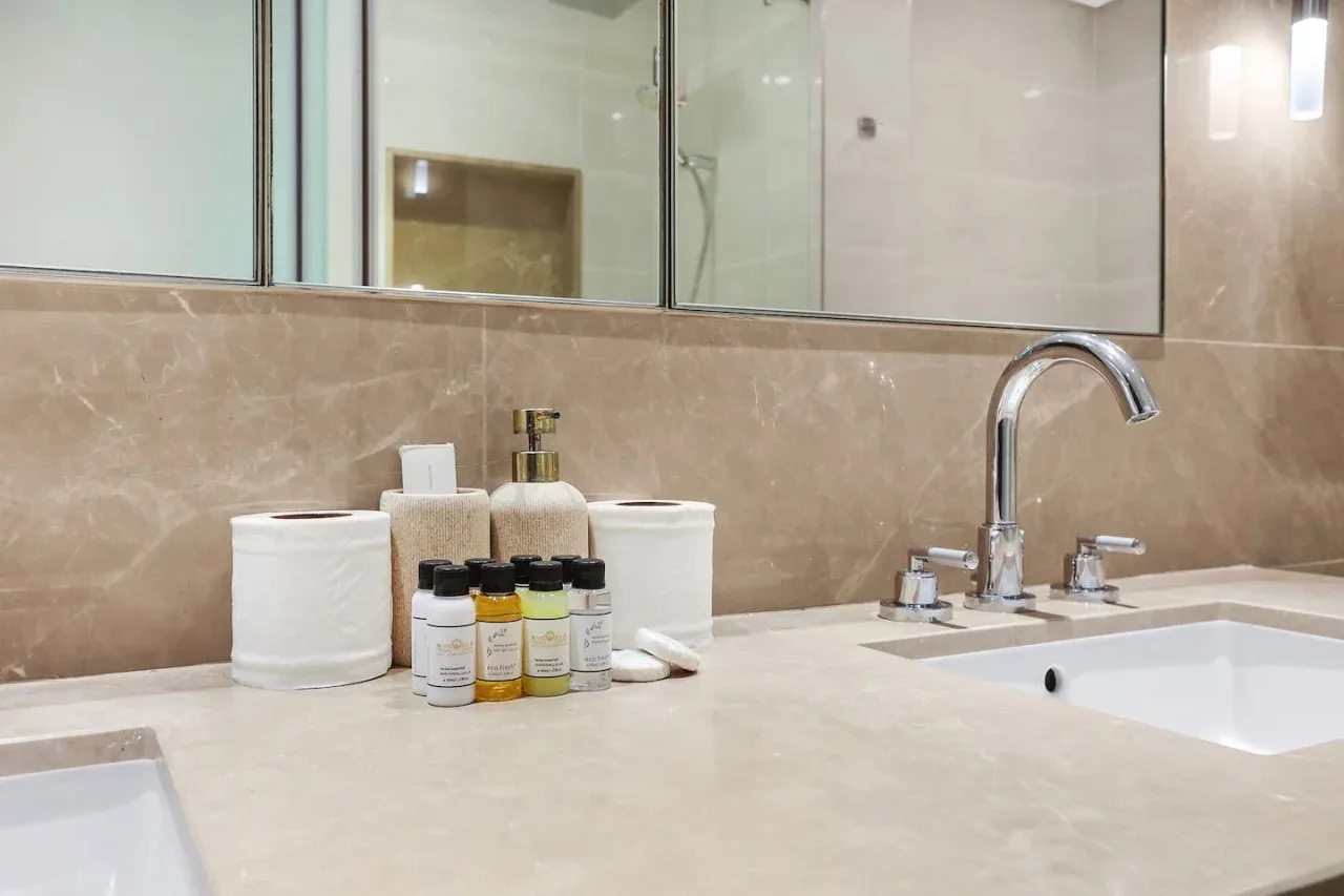 A bathroom vanity with a sink, toiletries, and a large mirror.