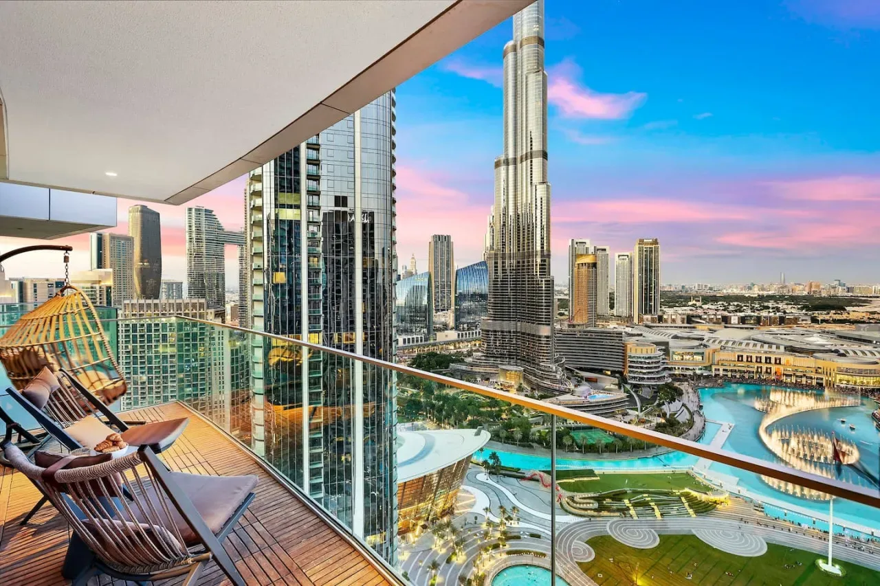 A balcony overlooks a city skyline and a landscaped pool area.