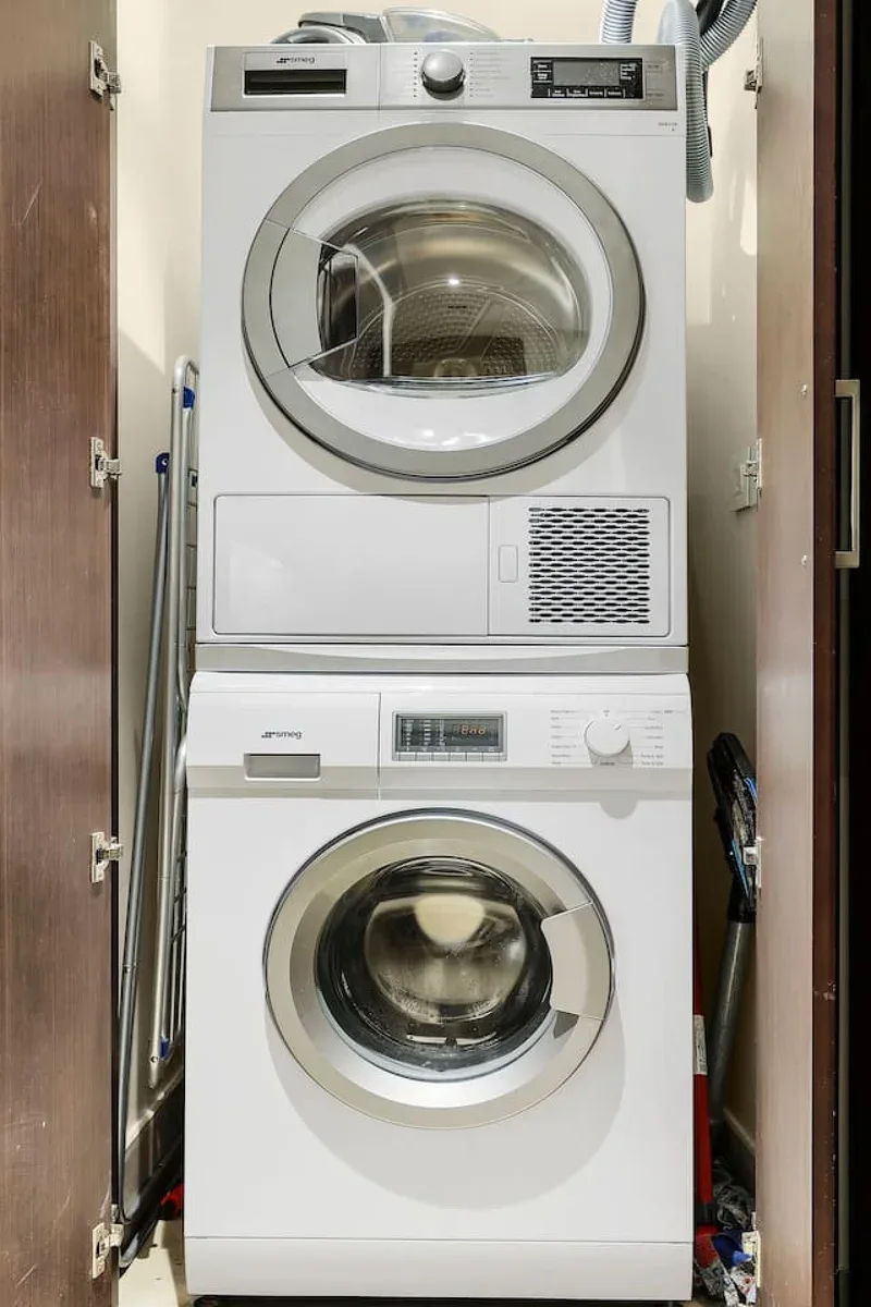 A laundry closet with a dryer stacked above a front-loading washing machine.