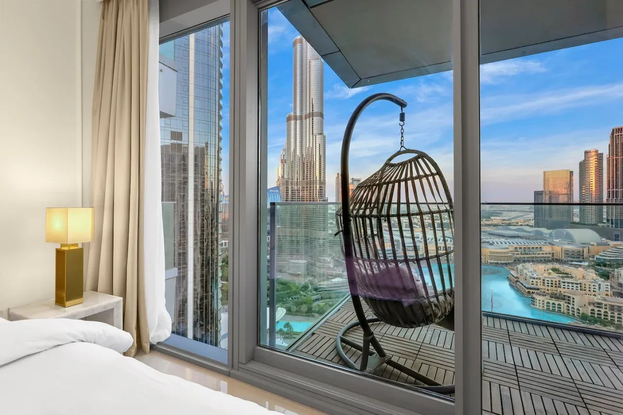 A bedroom opens onto a balcony with a hanging seat and city views.