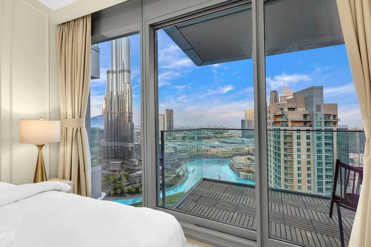 A bedroom opens onto a balcony with city views through large windows.