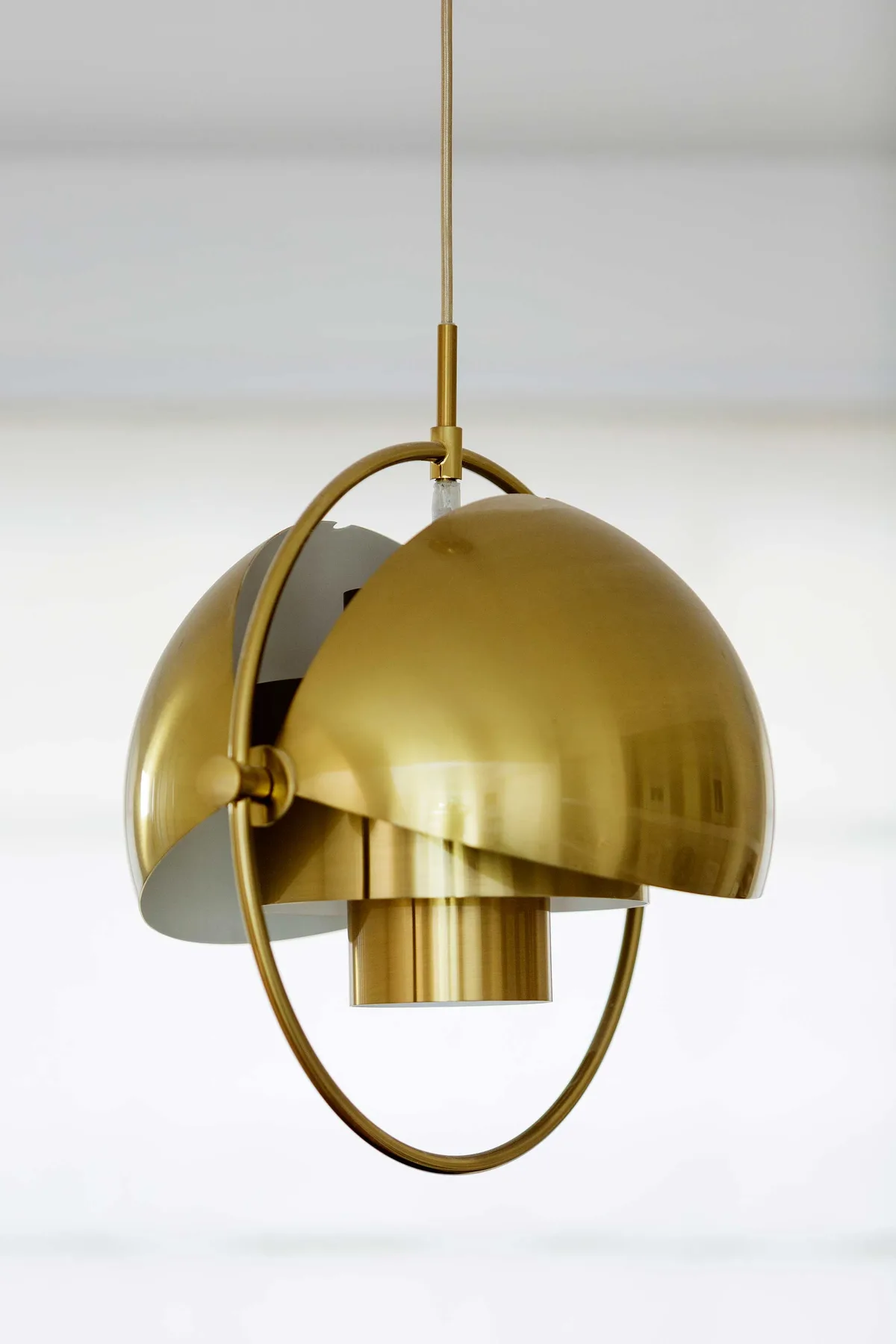A brass pendant light hangs against a plain white background.