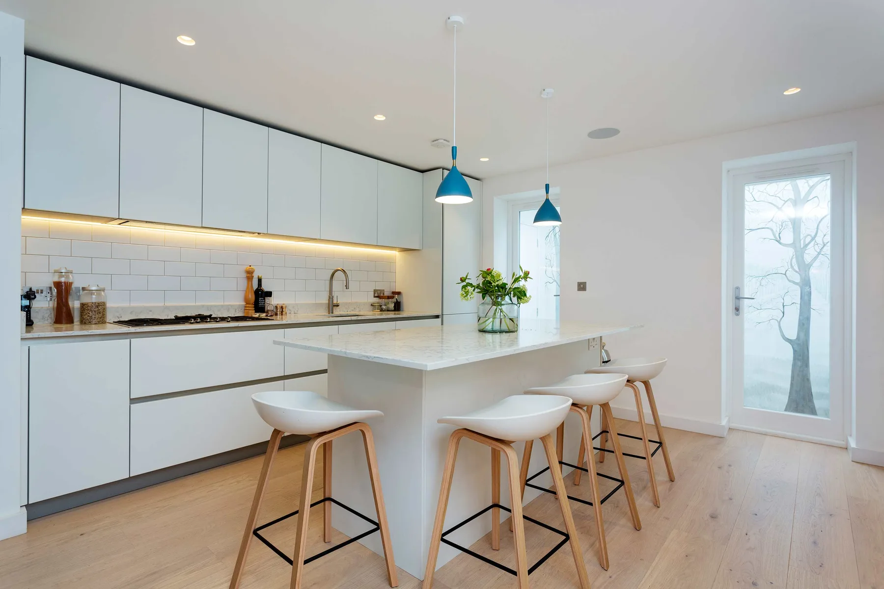 A bright modern kitchen has a long island with seating and pendant lights.