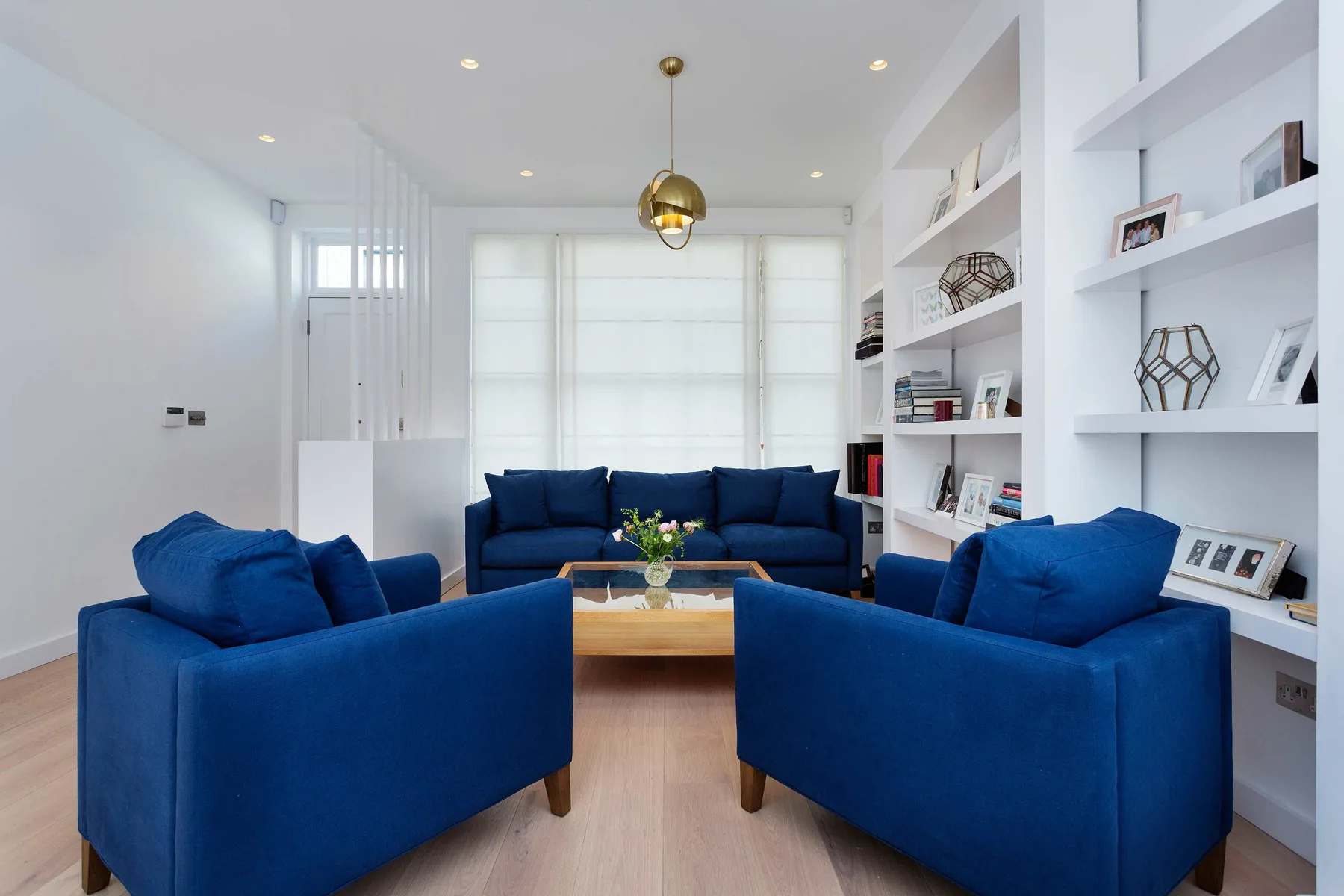 A bright living room with blue seating arranged around a low wooden coffee table.