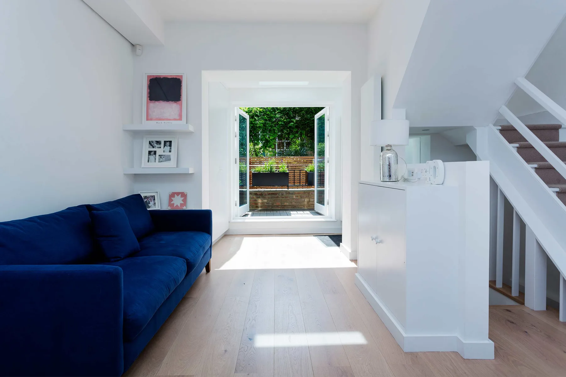 A bright living room with blue seating beside open doors to a garden.