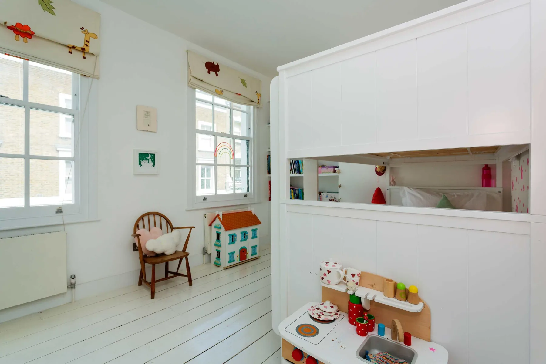 A bright playroom with a small play kitchen beside a white storage unit.