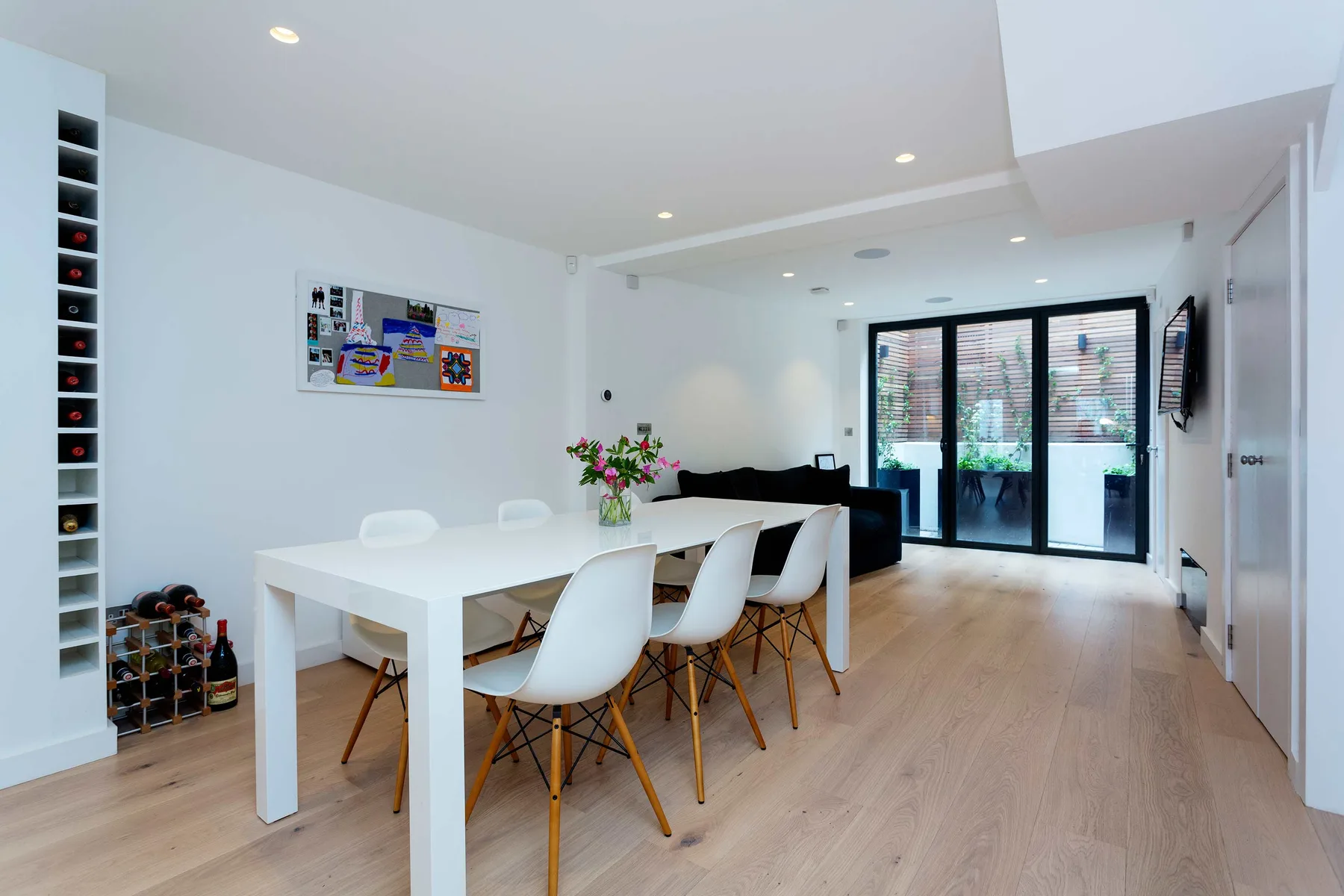 A bright dining area with a white table, chairs, and glass doors.