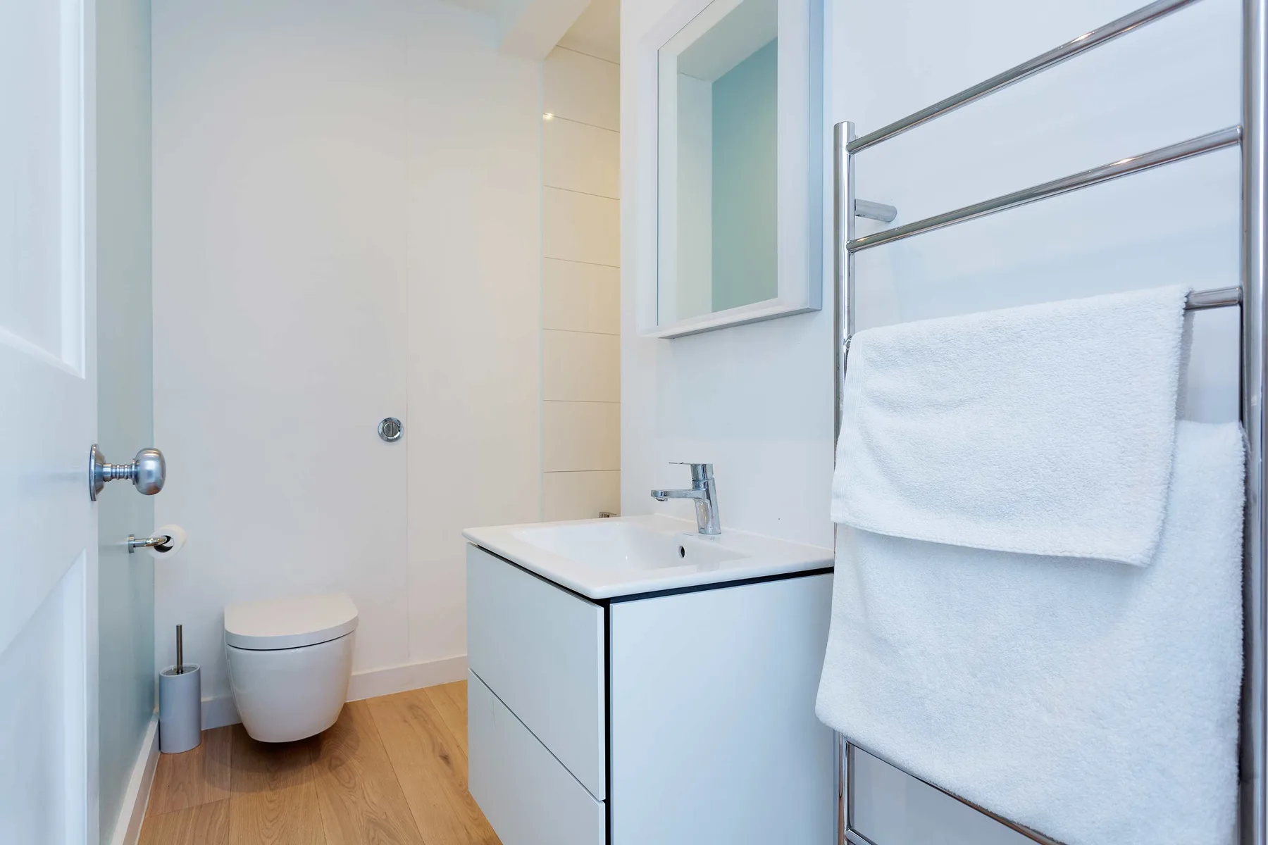 A bathroom with a sink, toilet, and towel rail.