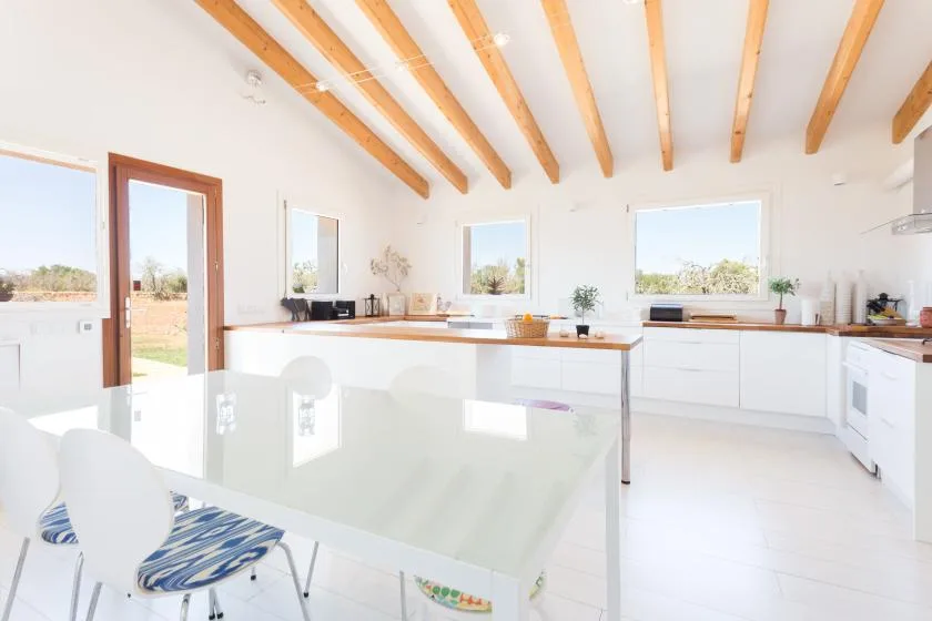 A bright kitchen with white cabinetry, a central island, and exposed ceiling beams.