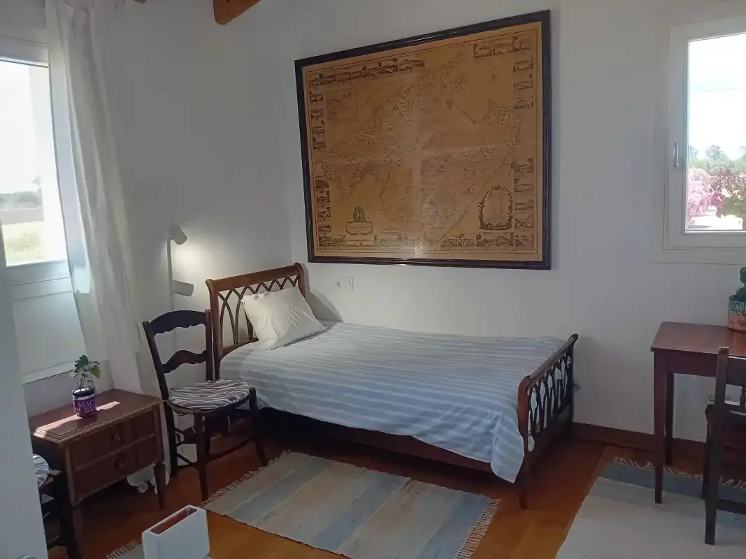 A bedroom with a bed, chairs, and a framed map on the wall.
