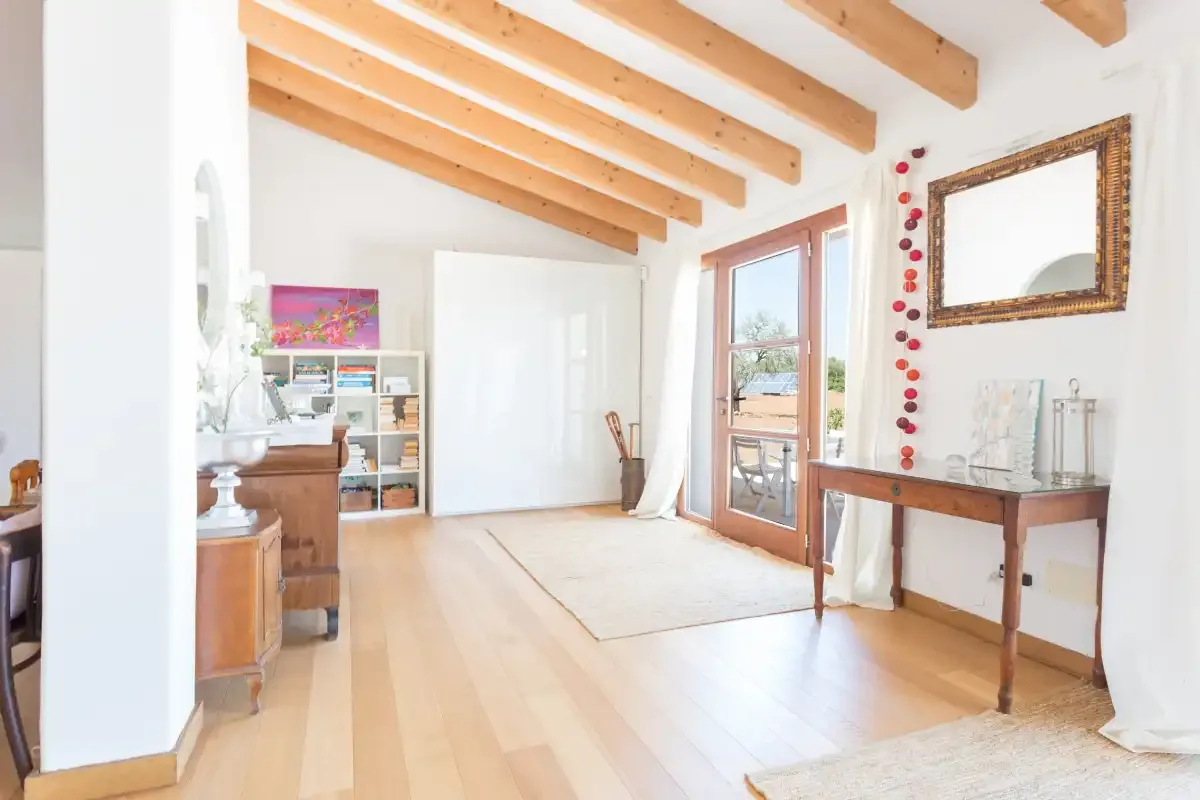 A bright living room with exposed wooden ceiling beams and glass doors.