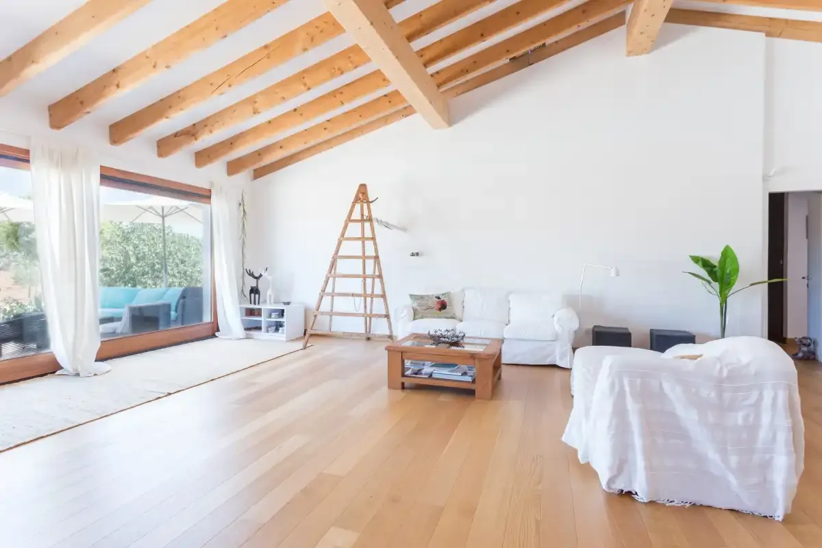 A bright living room with seating beneath exposed wooden ceiling beams.