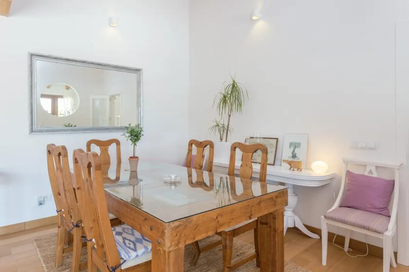 A dining area with a wooden table, chairs, and a large wall mirror.
