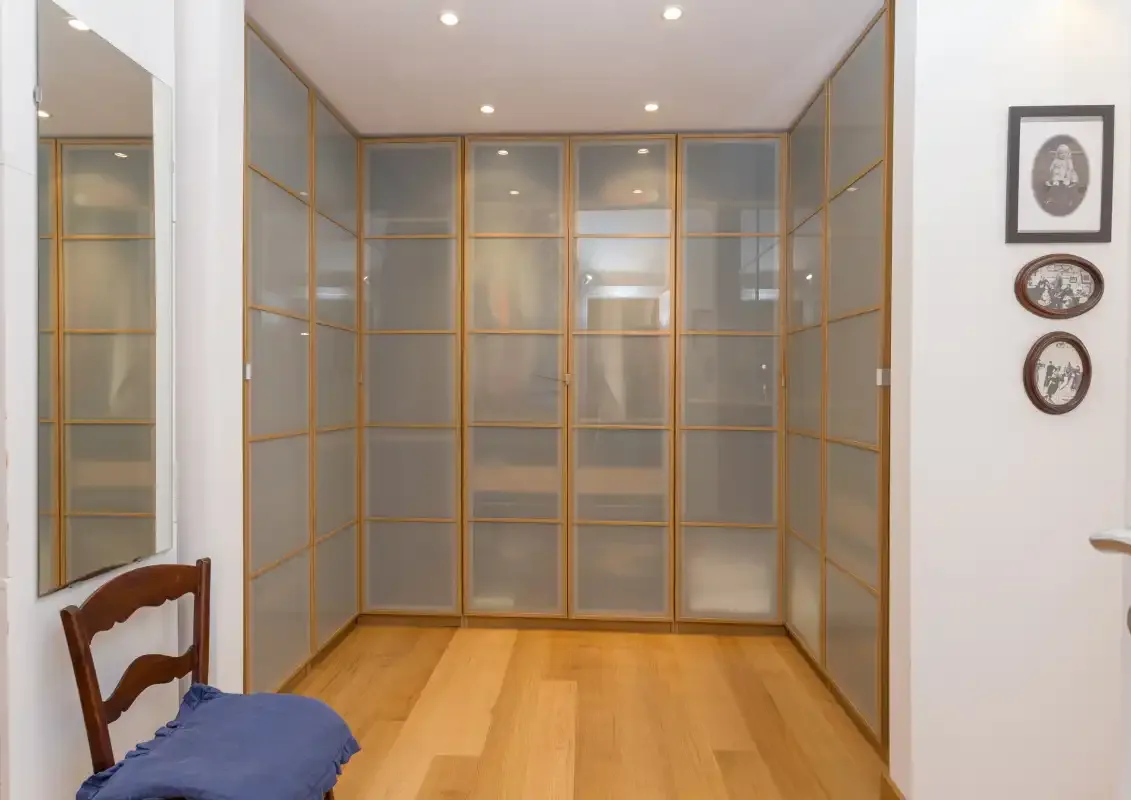 A dressing room with built-in wardrobes and wooden flooring.
