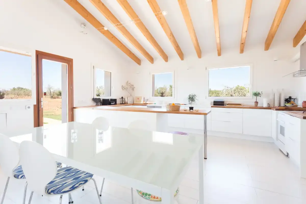 A bright kitchen and dining area with white cabinetry and a glass table.