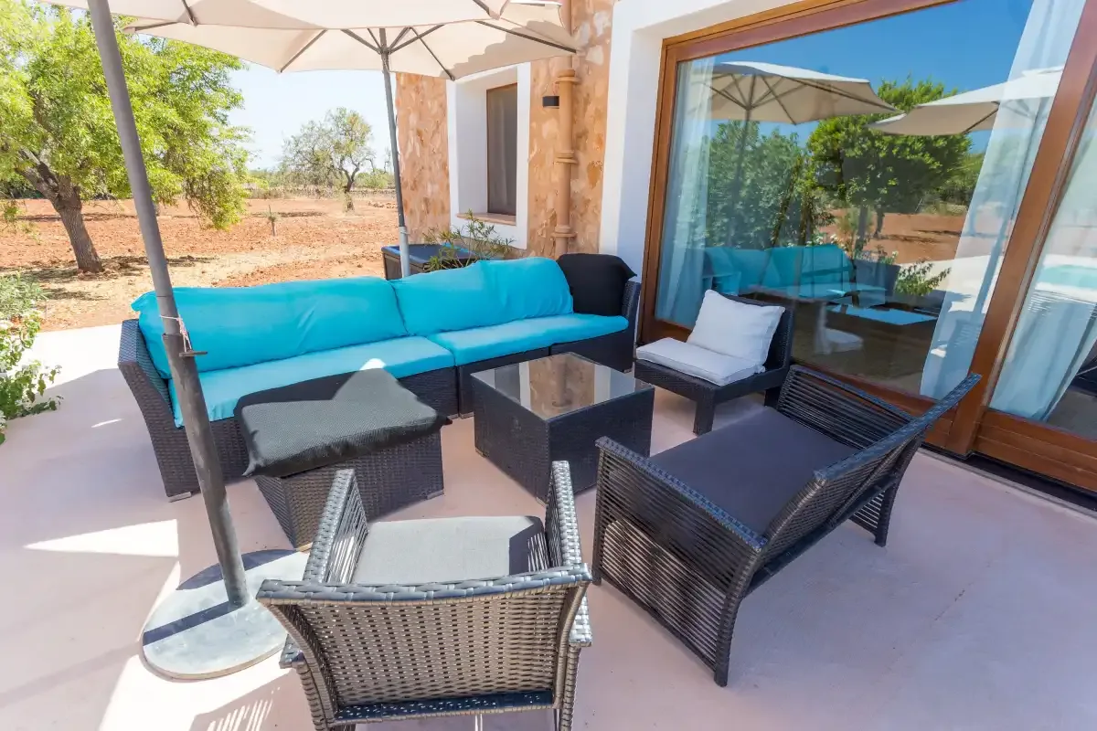 An outdoor seating area with cushioned furniture beside glass doors.