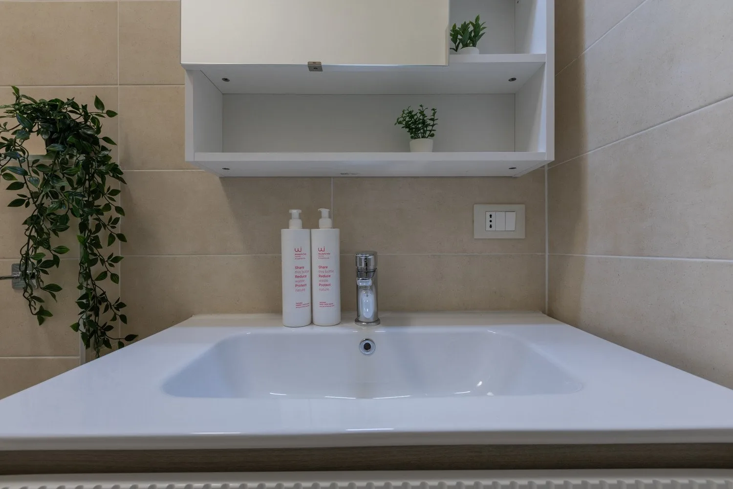 Un lavabo de baño blanco bajo estantes montados en la pared.