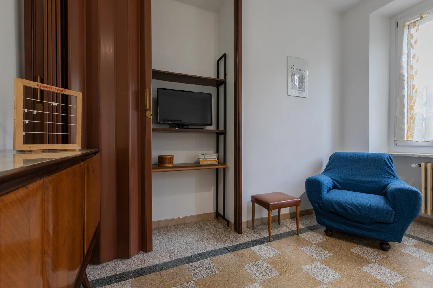 Una sala de estar con asientos azules, un televisor y una pequeña mesa de madera.