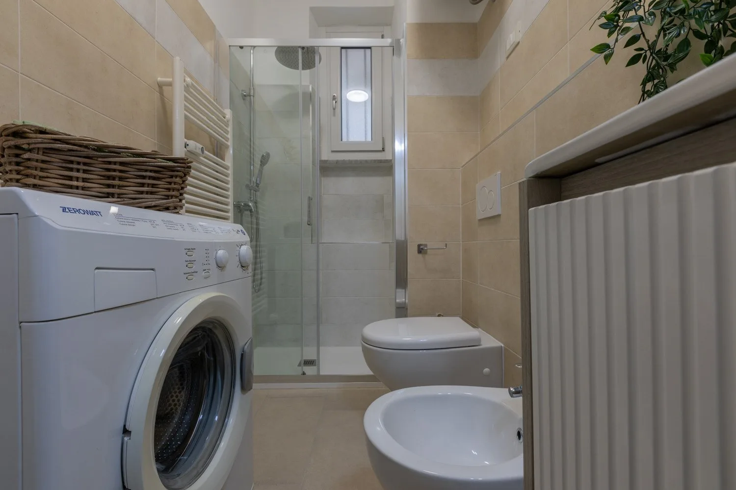 Un baño alicatado con lavadora, ducha, inodoro y bidé.