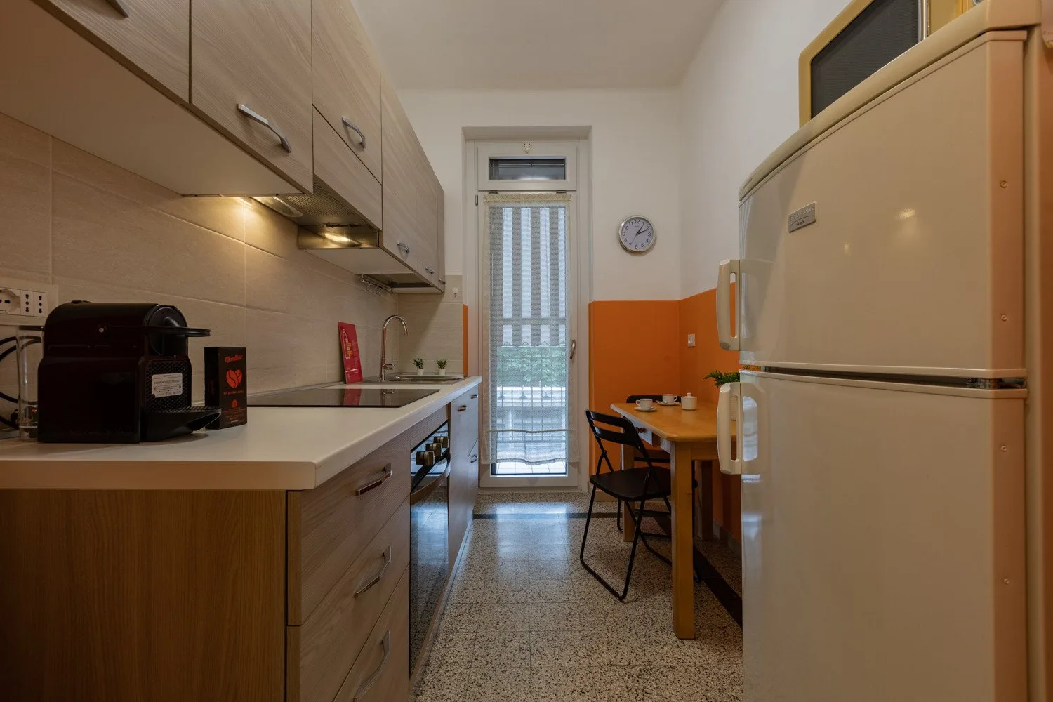 Una cocina estrecha con gabinetes de madera, una encimera y una pequeña mesa de comedor.