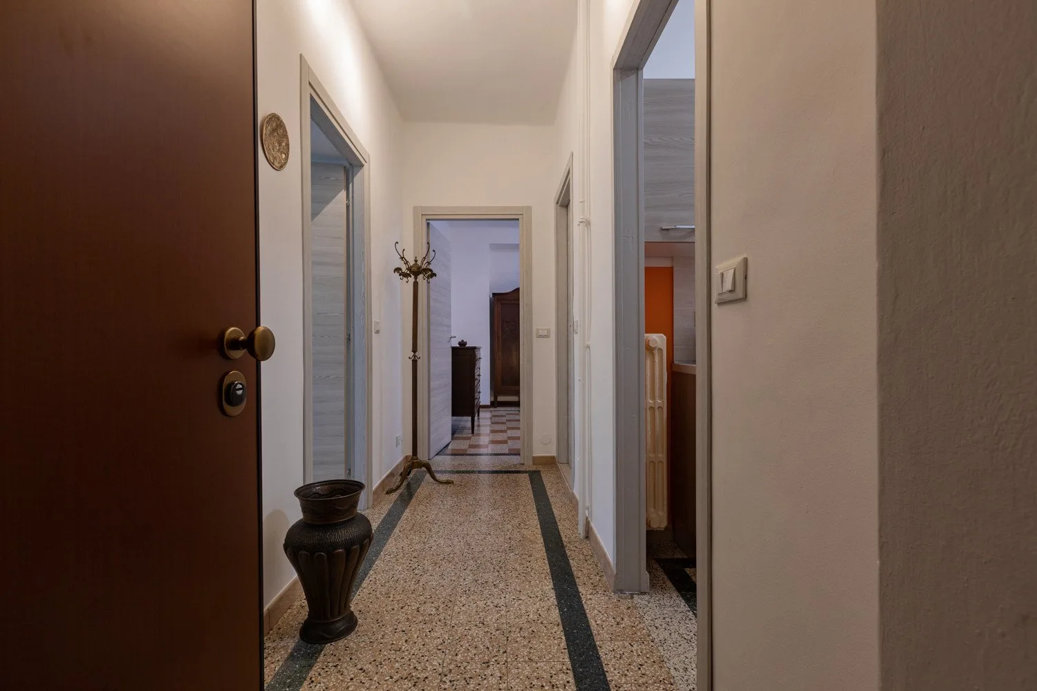 Un pasillo estrecho con suelo estampado conduce a varias puertas.